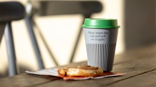 Returnable cup and a pastry on a napkin on a table outside the Box Hill cafe
